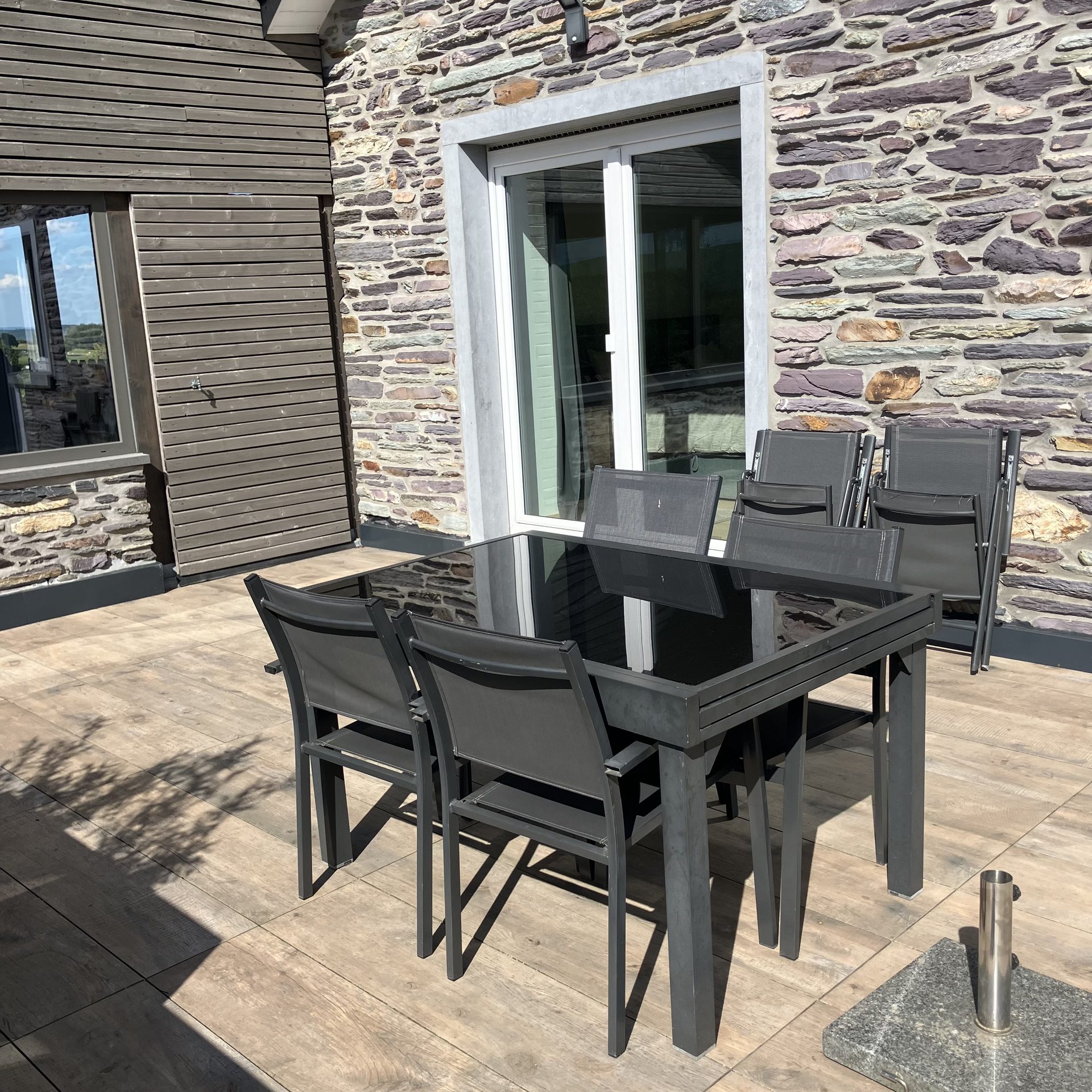 Table à manger et chaises sur la terrasse, devant la façade en pierre